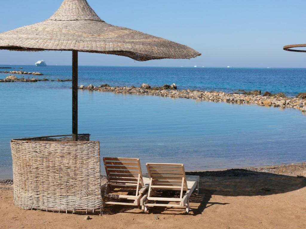 twee stoelen en een parasol op het strand bij Mini-Studio With Free Private Beach in Hurghada