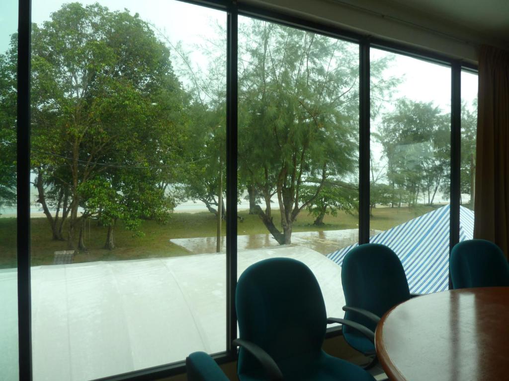 a room with a large window with chairs and a table at Cempaka Beach Resort in Kuantan