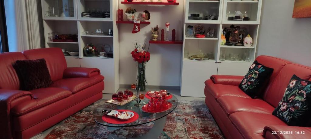 a living room with two red couches and a glass table at Luna di miele in Albosaggia