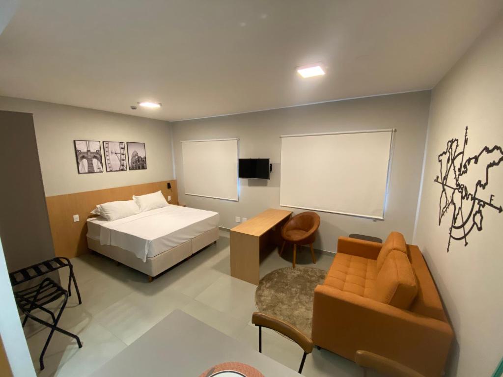 a bedroom with a bed and a couch and a chair at Flat em Alphaville - Super Novo in Barueri