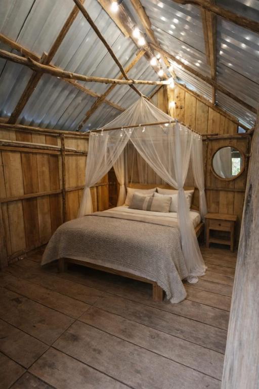 a bedroom with a canopy bed in a wooden house at Cabañas Kapuy in Florencia