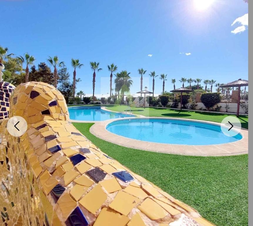 a large swimming pool in a resort with palm trees at Beachfront apartment in Oropesa del Mar