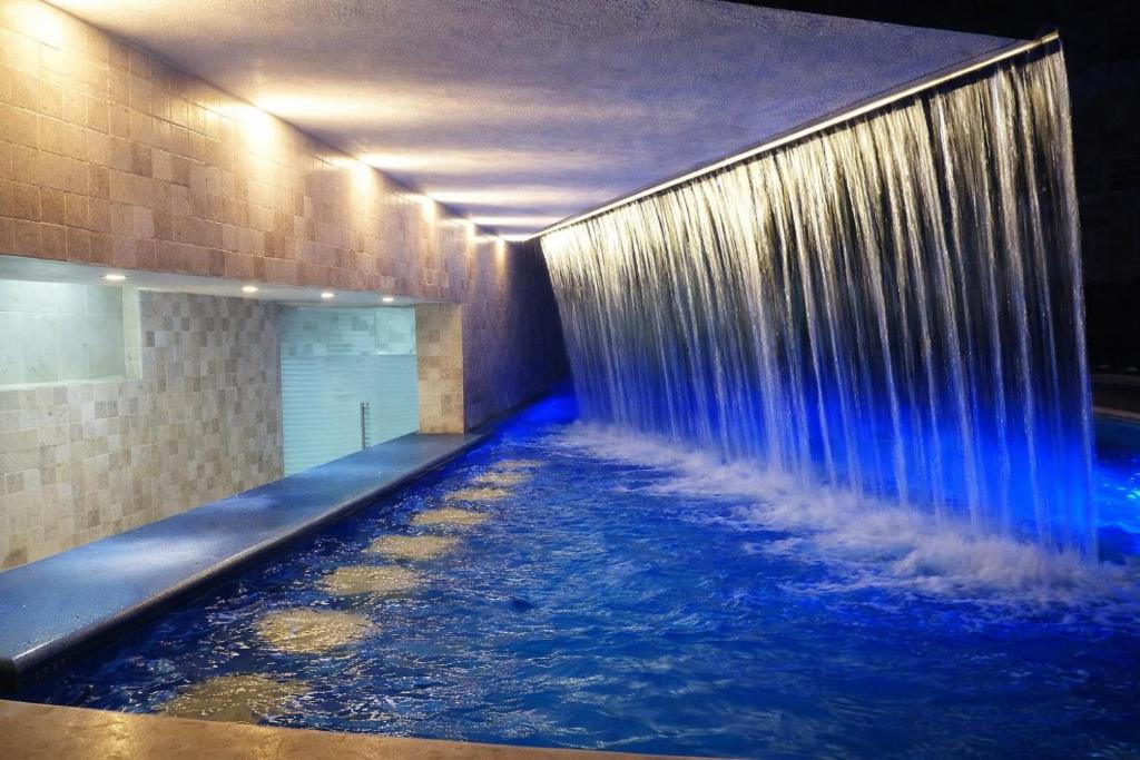 a swimming pool with a waterfall in a building at Estudio compacto en Riviera Diamante con alberca in Acapulco