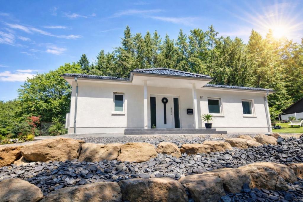 a small white house with a stone wall at Ferienhaus Waldblick in Hohenfels-Essingen