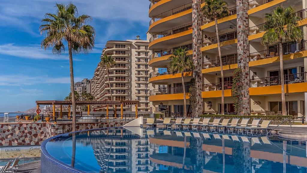 a hotel with a swimming pool and palm trees at Vacation Paradise Relaxing Ocean Front Condo in Puerto Peñasco