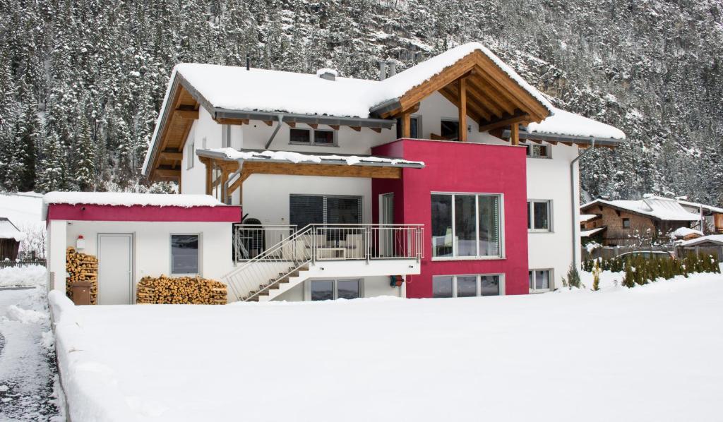 ein Haus im Schnee vor einem Berg in der Unterkunft Apart Bella Monte in Pettneu am Arlberg