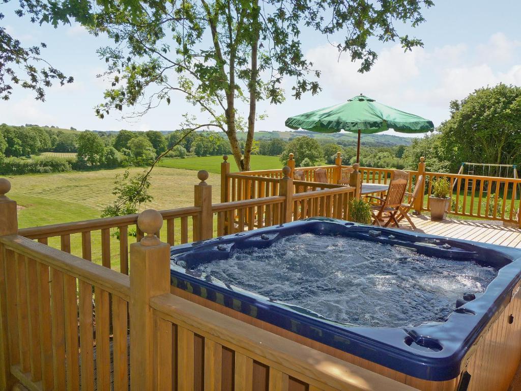 a hot tub on a deck with an umbrella at The Goyle-E4528 in Uplowman