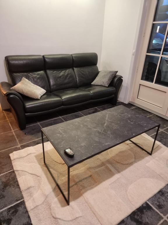 a black leather couch and a coffee table in a living room at Vacation at Emi's in Wetteren