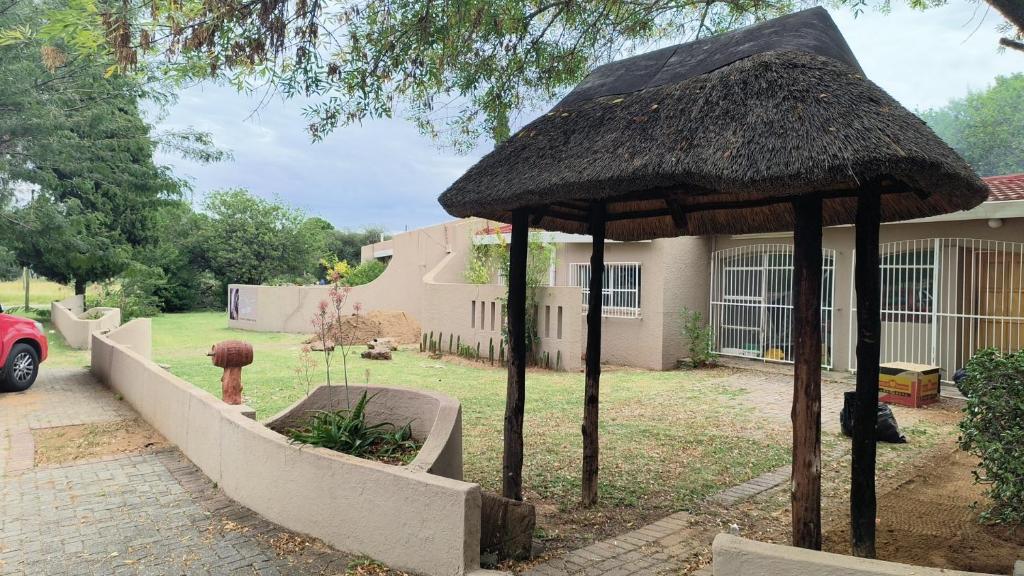 a house with a straw umbrella in the yard at Ave Maria Camping site in Welkom