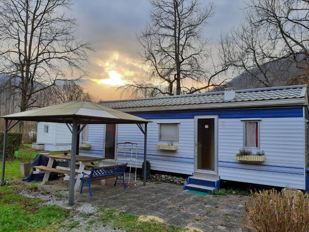 a blue house with a table and an umbrella at mobile home in Bielle