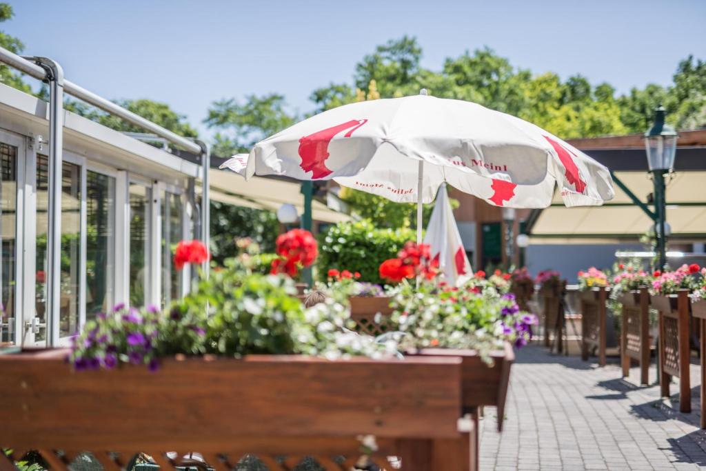 einen Tisch mit Blumen und einem Sonnenschirm auf einer Terrasse in der Unterkunft Hotel Eitljörg in Wien