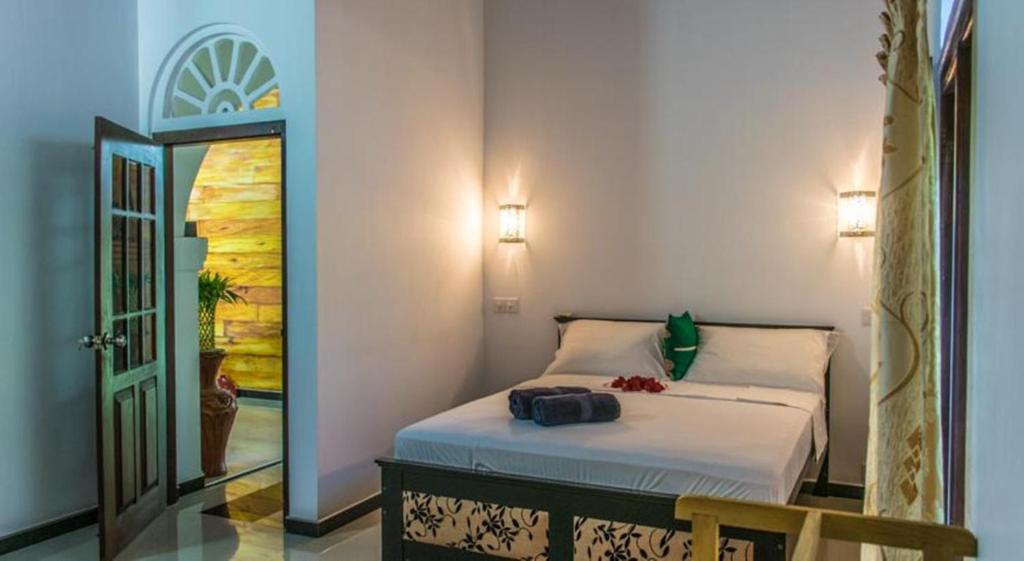 een slaapkamer met een bed, een spiegel en een deur bij Villa Ali in Galle