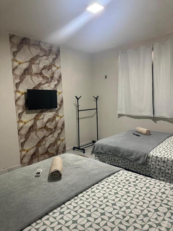 a bedroom with two beds and a flat screen tv at Pousada Nova Betânia in Mossoró