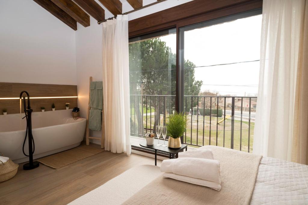 a bedroom with a large window and a bath tub next to a bed at Casita Romántica con Suite y Bañera en la Sierra "Colladito de Alce" in Collado Hermoso