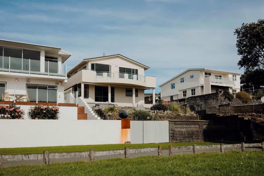 a row of houses behind a white fence at Oceanfront Retreat - Beach Access - 2BR Bell Block in New Plymouth