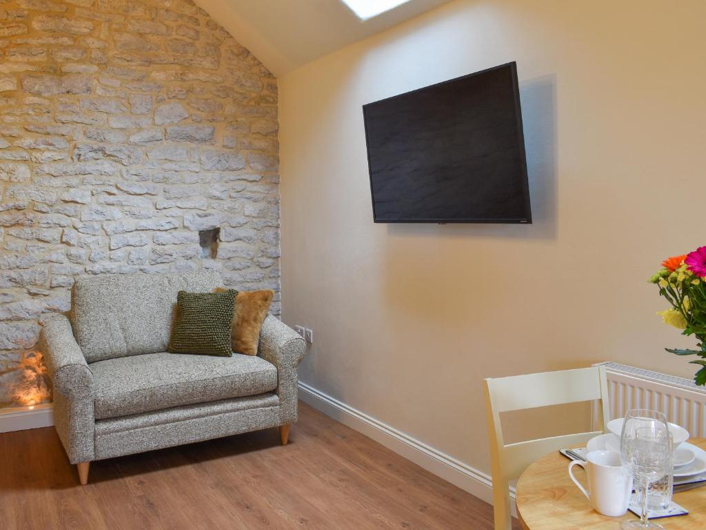 a living room with a chair and a tv on the wall at The Loft - Uk50284 in Earl Sterndale
