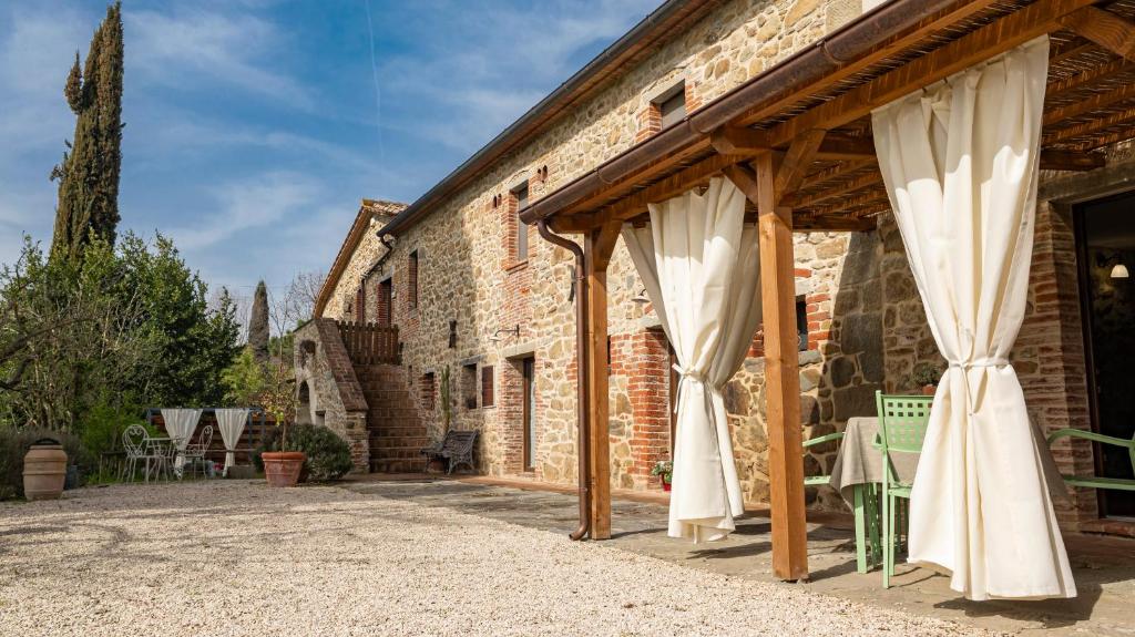 a patio with white curtains on a brick building at Agriturismo L'Accolta in Tuoro sul Trasimeno