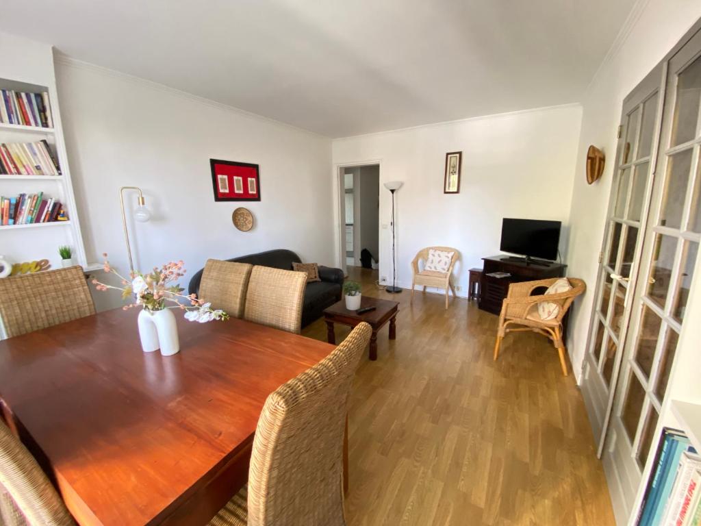 a dining room and living room with a wooden table at Quiet Stay near Paris - Balcony & Private Parking in Châtillon