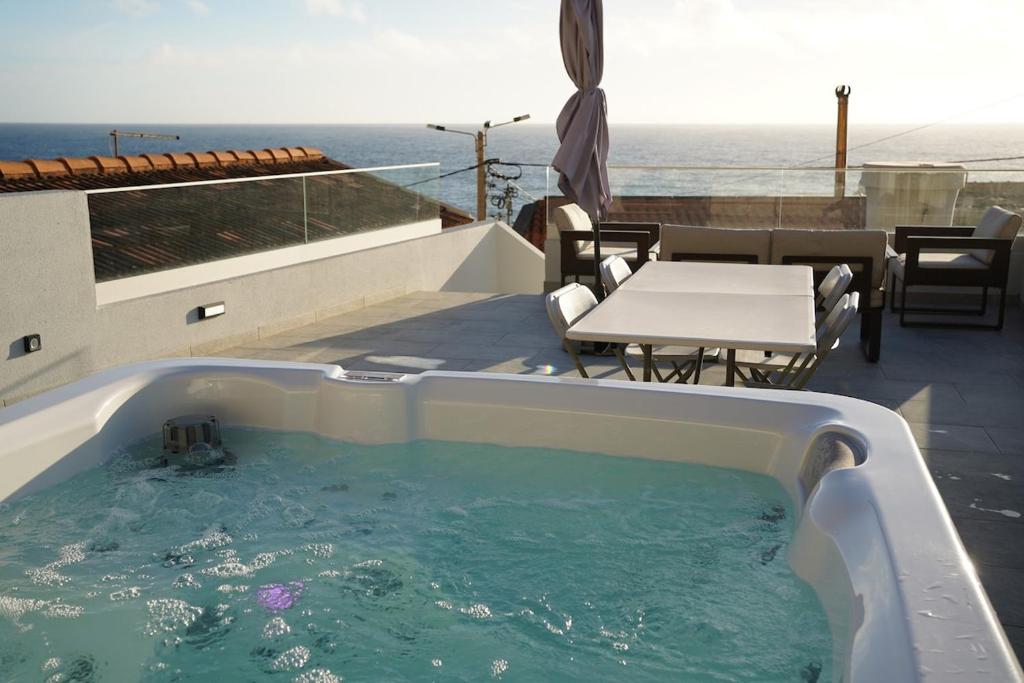 a hot tub on top of a patio with a table at Pauloldtown - Local experience w rooftop n jacuzzi in Paul do Mar