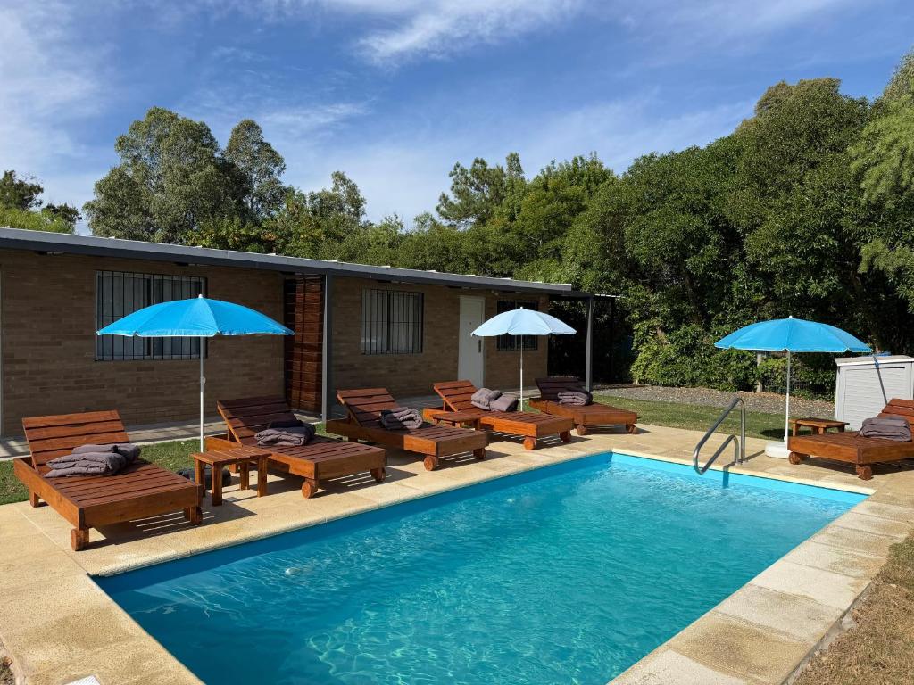 a swimming pool with patio furniture and umbrellas at Complejo San San in San Luis