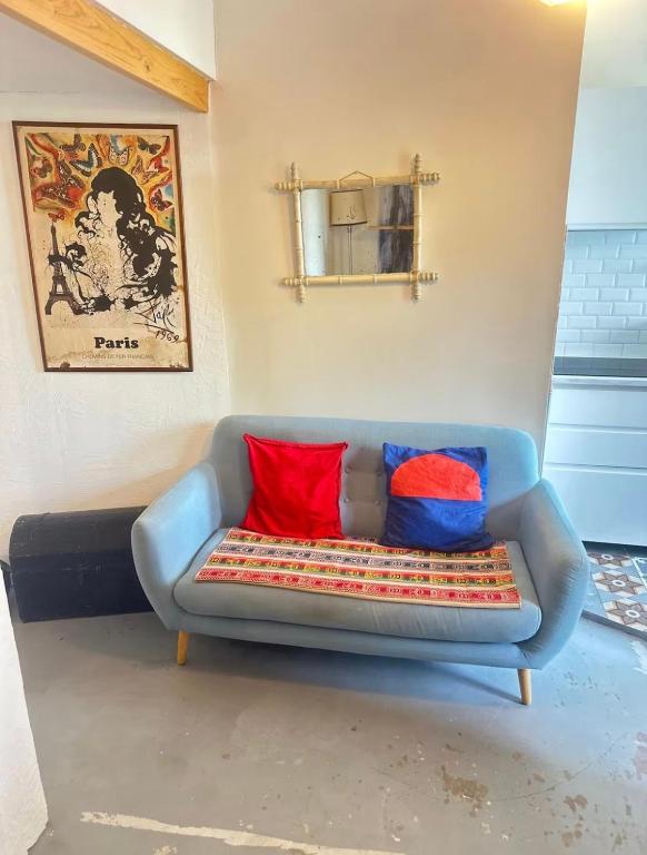 a blue couch with red and blue pillows on it at Petit nid calme à 2 pas de Paris in Ivry-sur-Seine