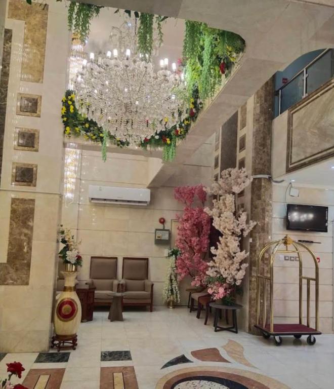 a lobby with a chandelier and chairs and flowers at فندق جوهرة ذاخر رويال توصيل مجاني للحرم - Jewel Thakher Royal Hotel Free Shuttle to Haram in Mecca