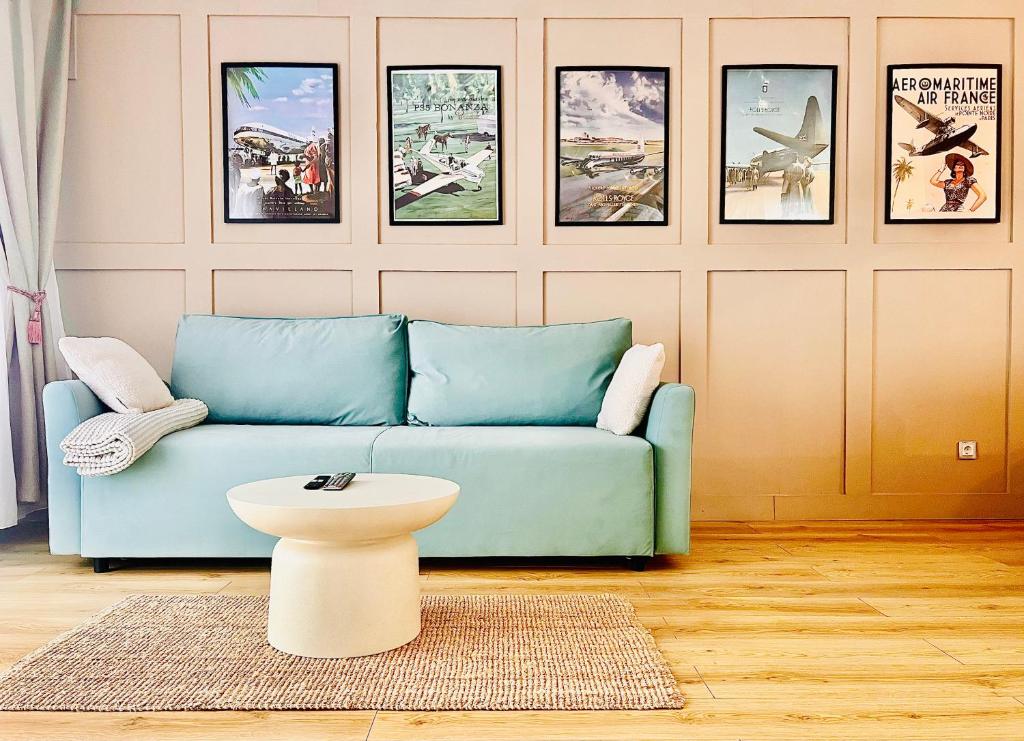 ein Wohnzimmer mit einem blauen Sofa und Bildern an der Wand in der Unterkunft Otopeni Airport Apartment - King Bed - Free Shuttle Included Near Therme in Otopeni