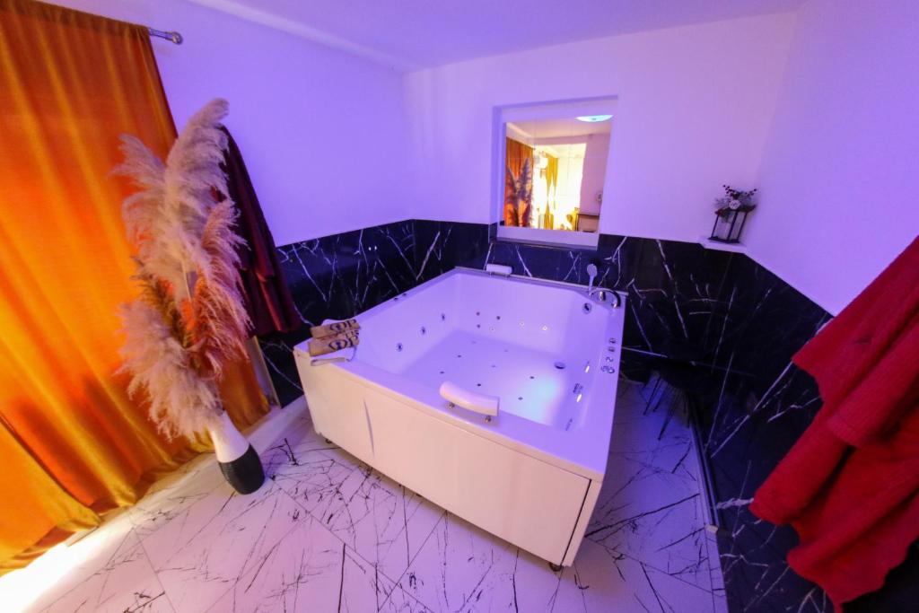 a bathroom with a tub with black marble floors and a mirror at Hedonist Spa Jacuzzi Centar Free private parking in Sarajevo