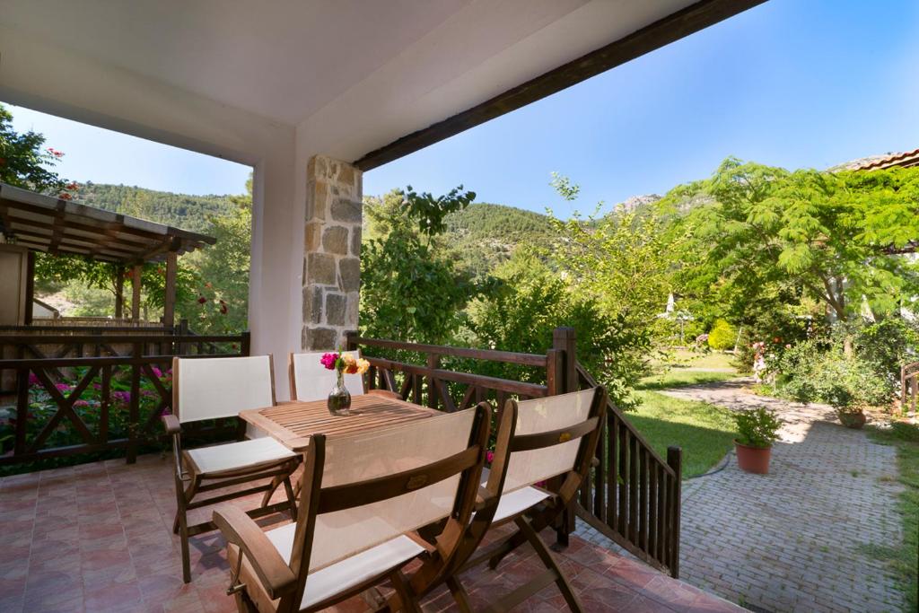 a patio with a wooden table and chairs on a balcony at Menir Apartments in Prinos