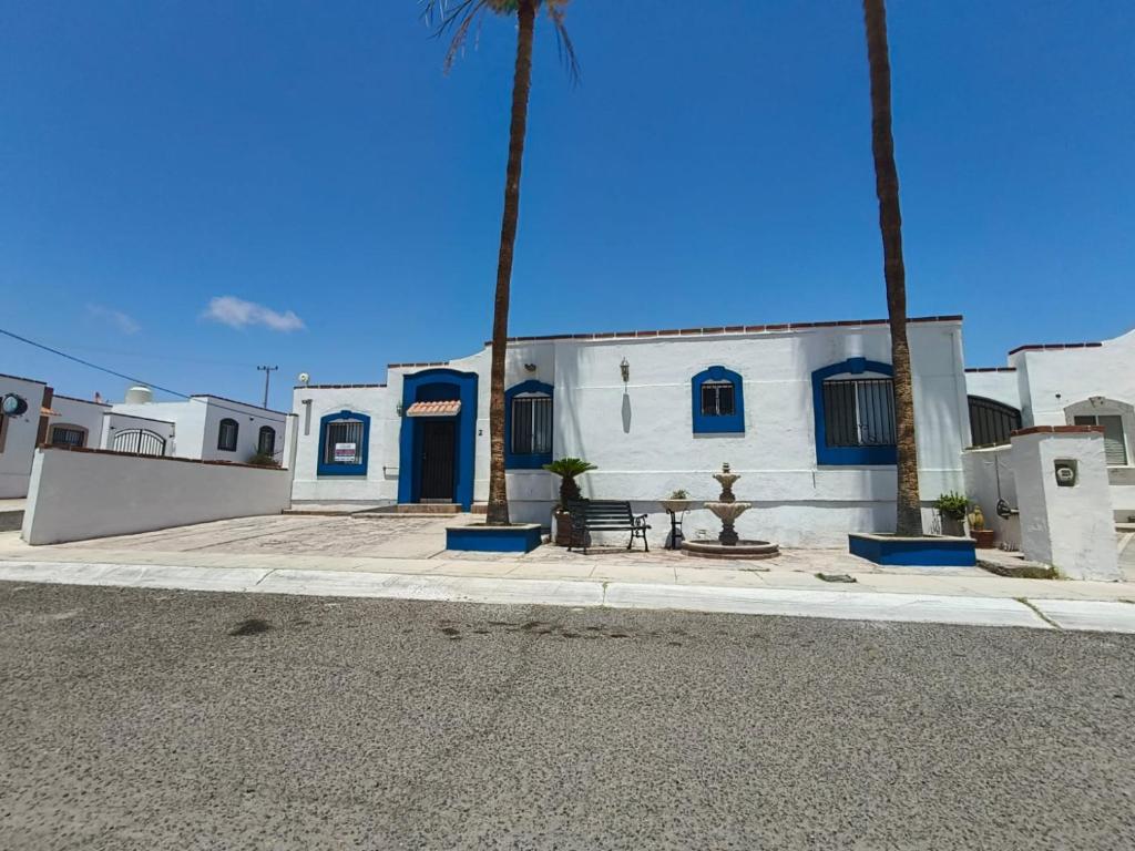 a white building with blue doors and a bench on the street at Villa Serena Erizos 2 in San Carlos