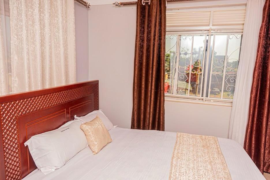 a bedroom with a bed and a window with at Alma Hotels Kampala in Kampala