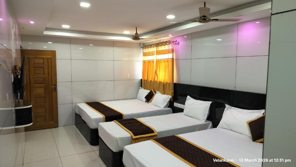 a room with two beds and a couch at Hotel Grand Arputha in Velankanni