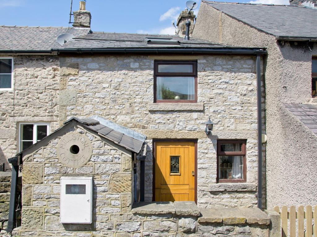 an old stone house with a yellow door at Millstone Cottage in Bradwell
