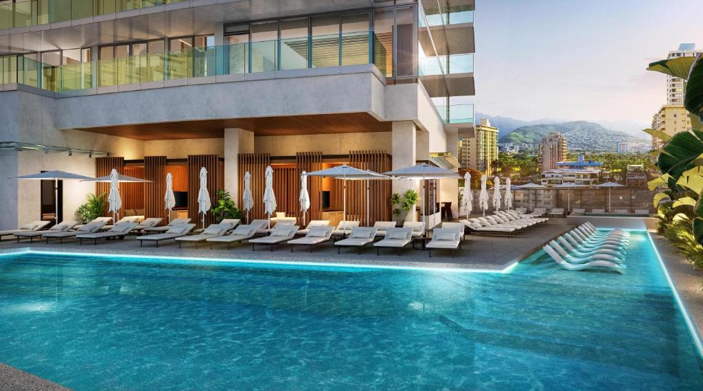 a swimming pool with lounge chairs and a building at Hilton Club Ka Haku Honolulu in Honolulu