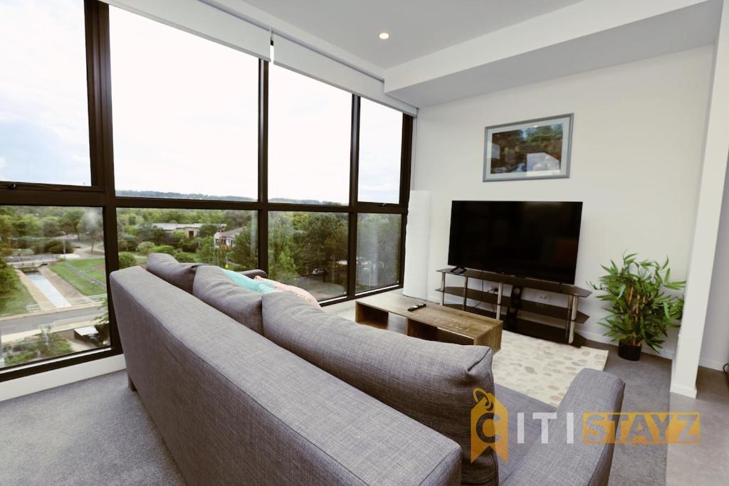 a living room with a couch and a flat screen tv at Lovely in Lyneham - 1bd 1bth Apt in Canberra