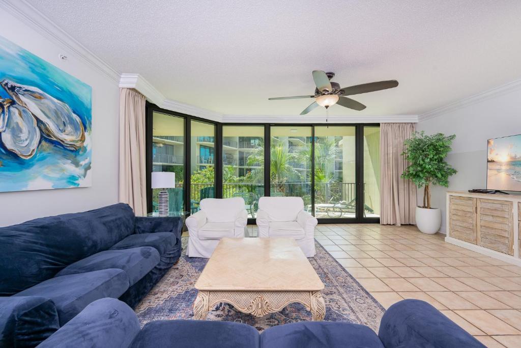 a living room with a blue couch and a ceiling fan at Phoenix on the Bay 1217 in Orange Beach