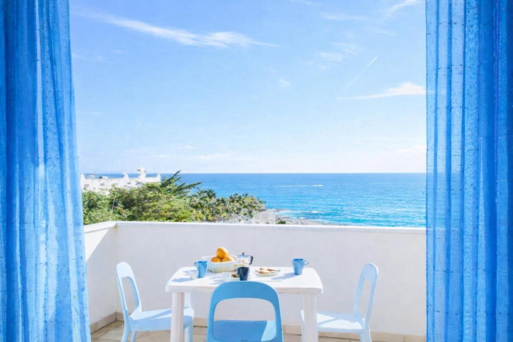 a table and chairs on a balcony with the ocean at ONDA BLU-Appartamenti in Torre dell'Orso