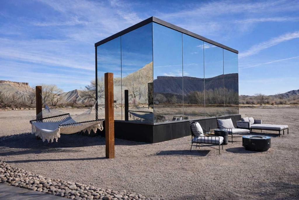 a glass pavilion with furniture in a desert at Luxury Glass Tiny House and Sauna in Torrey