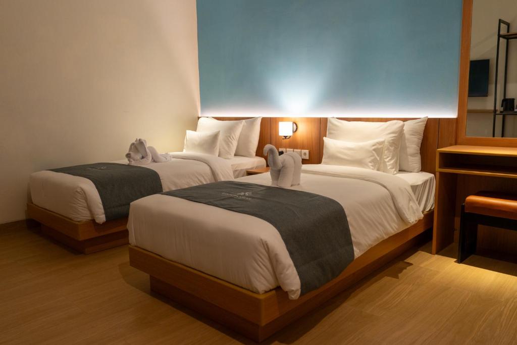 a hotel room with two beds and a mirror at Anamcara Hotel & Convention in Cipanas