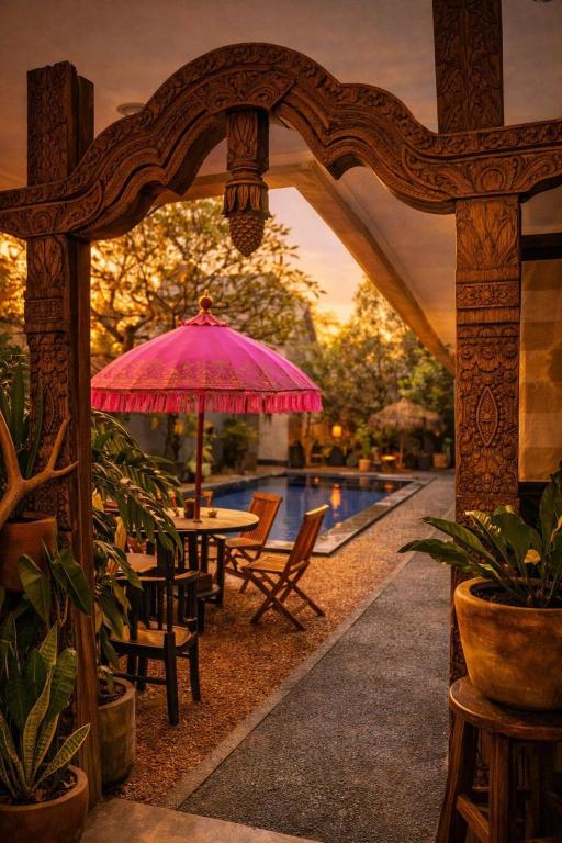 a patio with a table and umbrella and a pool at Tendan Residence in Legian
