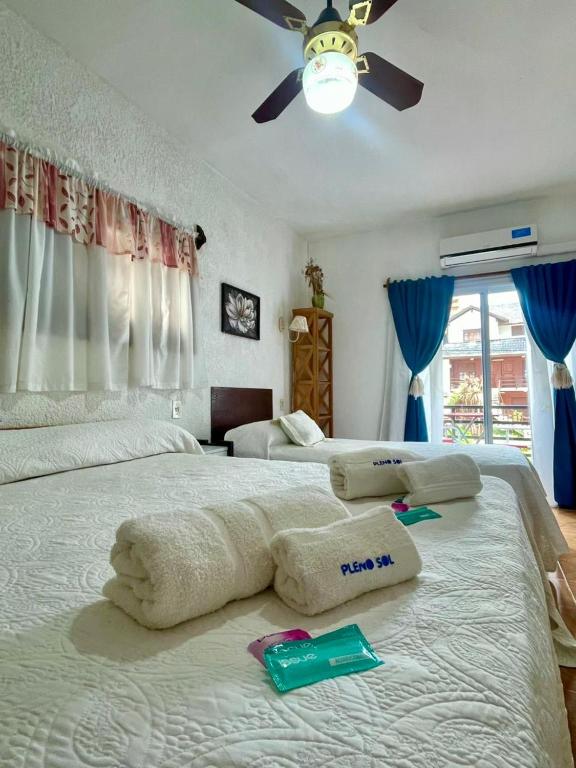 a bedroom with two beds with towels and a ceiling fan at Hotel Pleno Sol in Villa Gesell