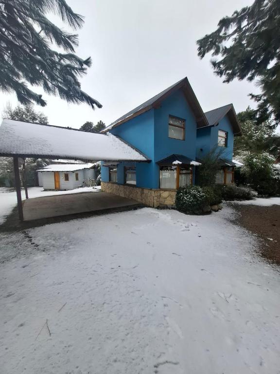 a blue house with snow in front of it at Aromas de Montaña VIP in Junín de los Andes