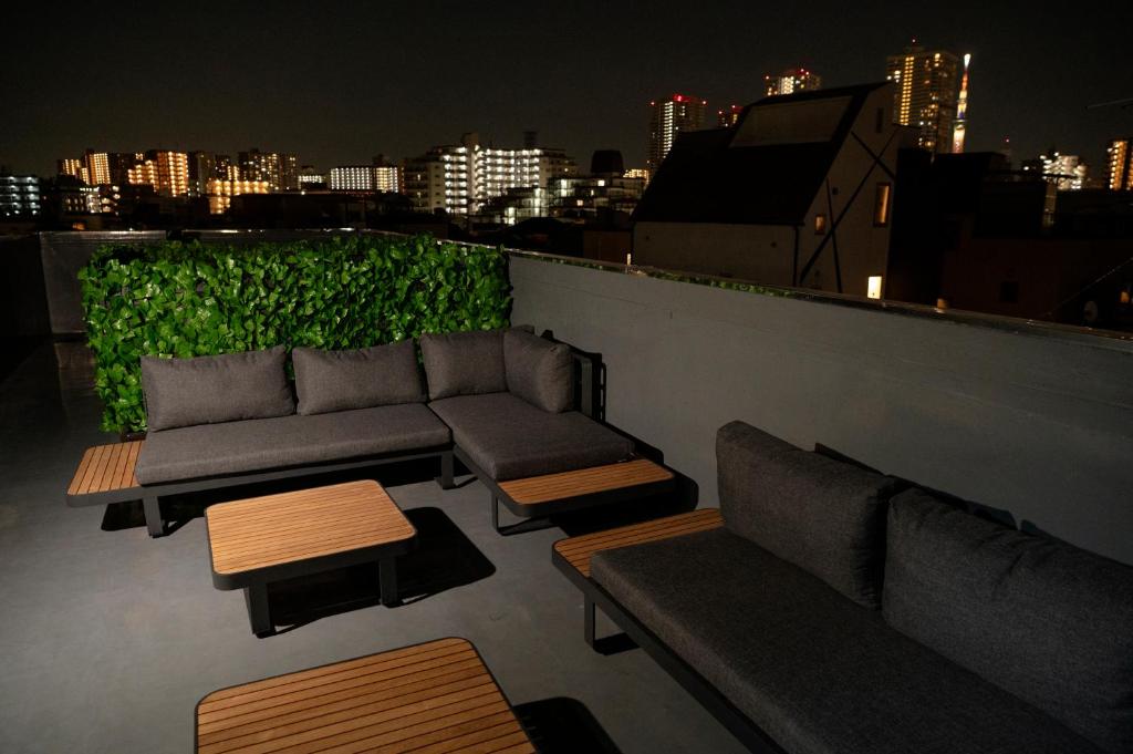 a patio with couches and tables on a rooftop at night at Edo stay senju in Tokyo