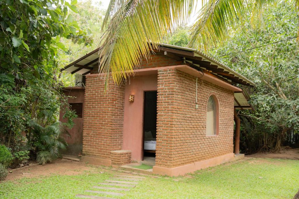 a small brick building in the middle of a forest at Sayon River Cottage in Wellawaya