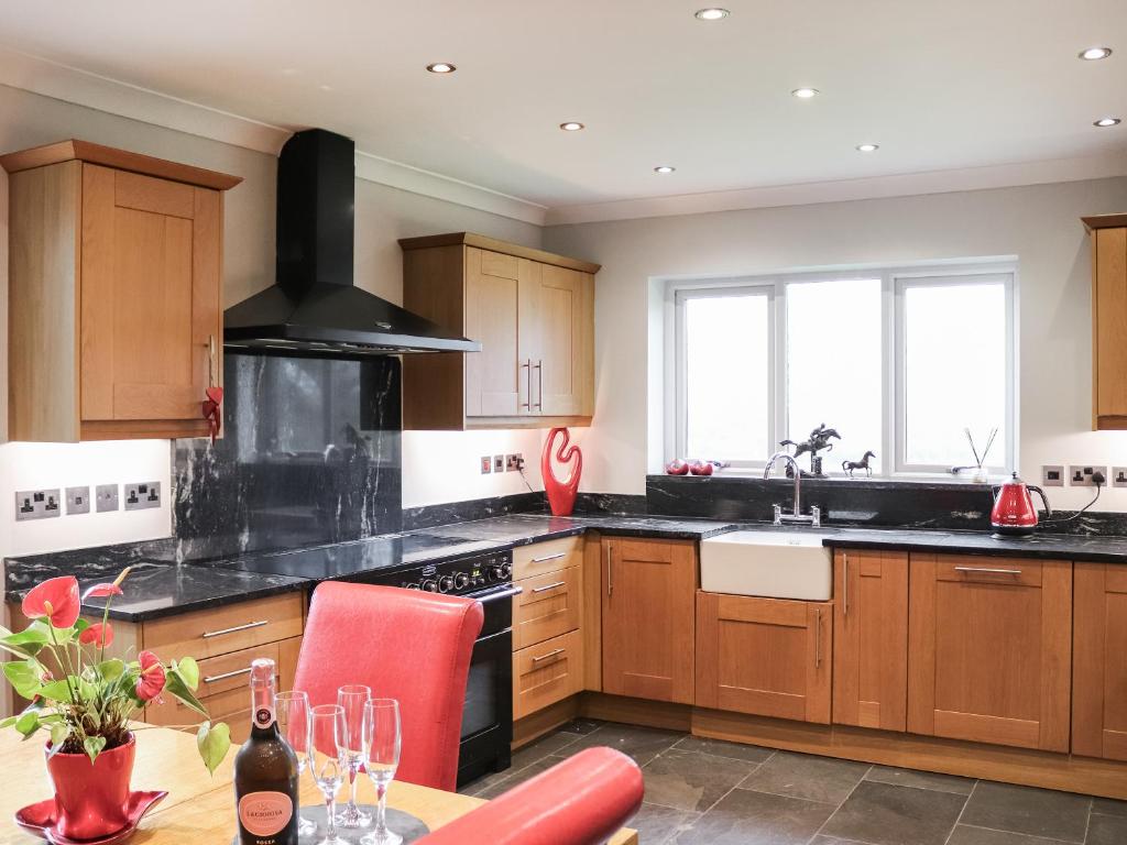 a kitchen with wooden cabinets and a stove top oven at Ty'n Rallt in Bodorgan
