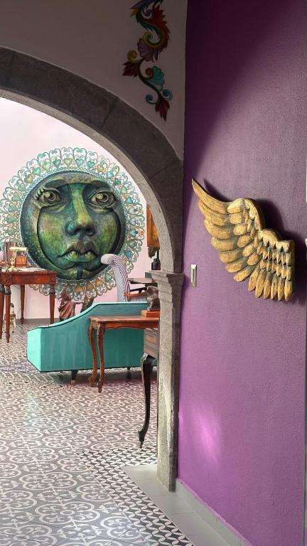 a wall with a statue of a face with a wings at Macondo Hotel Galería in San Luis Potosí
