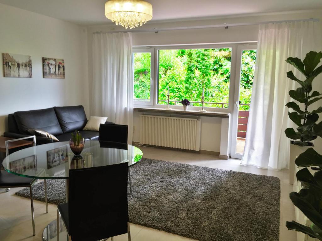 a living room with a glass table and a couch at Apartment - zentrumsnah, eigener Parkplatz und großer Balkon ins Grüne in Baden-Baden