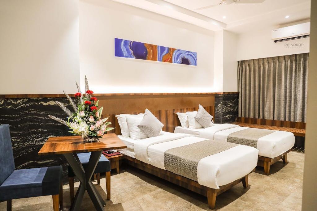 a hotel room with two beds and a table at Hotel Paradise Ahilyanagar in Ahmadnagar