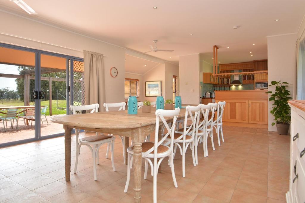 a kitchen and dining room with a wooden table and chairs at JE Guesthouse, central to all the Hunter Valley has to offer in Pokolbin