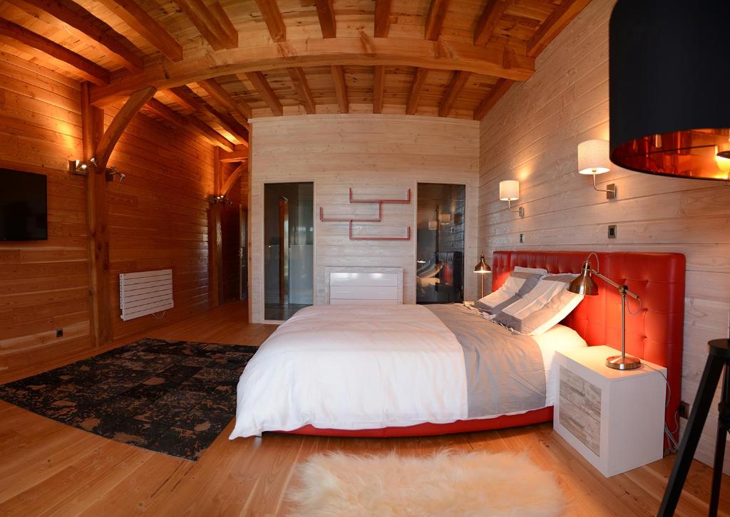 a bedroom with a large bed in a room with wooden walls at Domaine du Mont Monnet - Chambre d'hôtes & Gîte in Longes